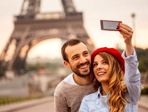 Entradas Torre Eiffel con audioguía: visitante escuchando junto a la torre